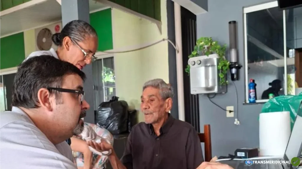 Equipe técnica da Politec e da Prefeitura de Colíder realizando coleta biométrica móvel para emissão da Carteira de Identidade Nacional na residência de morador acamado.