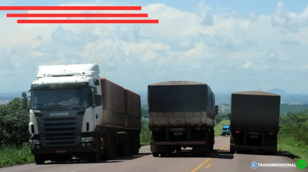 Três carretas trafegando na rota dos grãos, duas indo e uma vindo, ceú azul na paisagem.